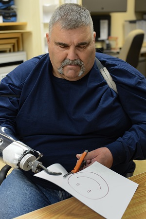 Veteran missing a right hand (hook attached in it's place) is using scissors and doing cratfts